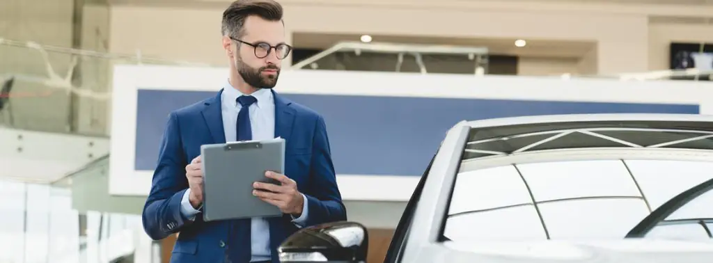 gestor segurando prancheta ao lado do carro