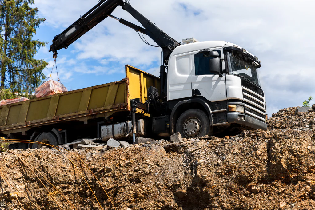 Caminhão munck com braço de guindaste descarregando materiais de construção.