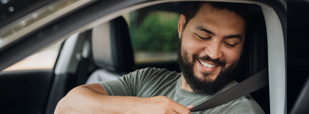 homem colocando o cinto de segurança no carro com alegria