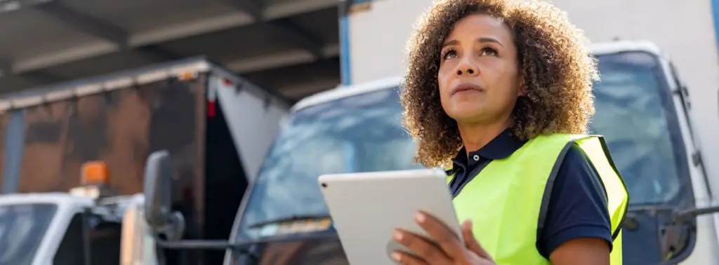 mulher usando tablet em frente ao caminhão