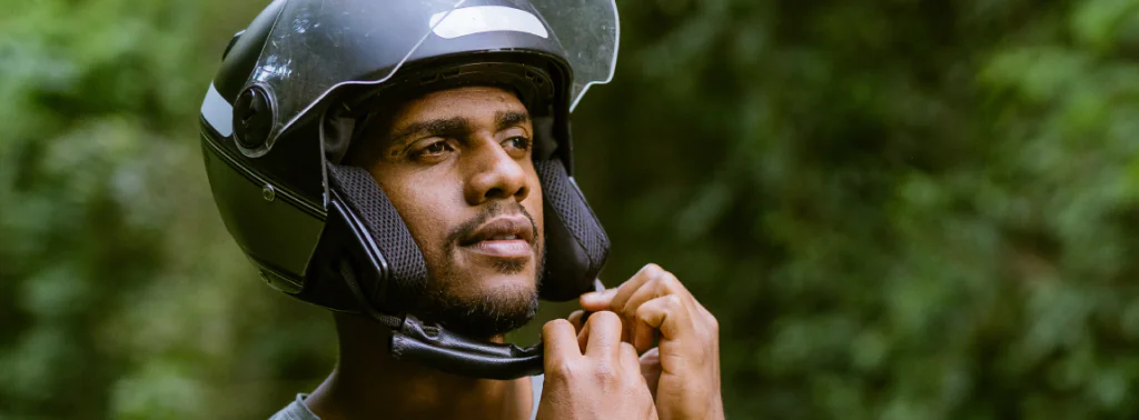 homem fechando o capacete de sua moto para enfrentar o trânsito